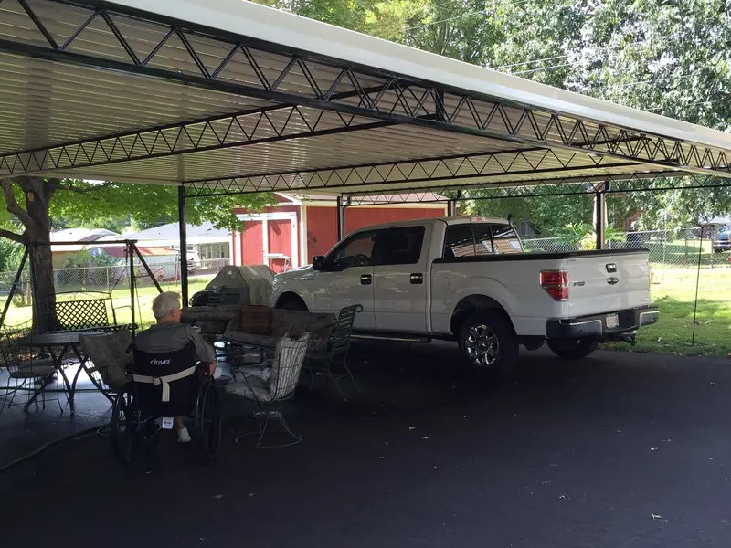 Large freestanding carport sheltering a pickup truck and a patio seating area