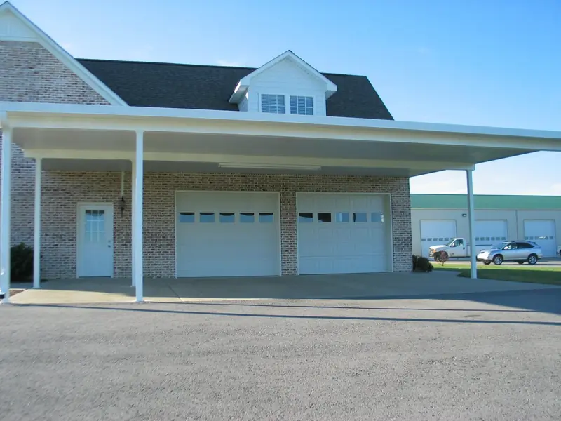 Wide aluminum carport across the front of a two-car garage
