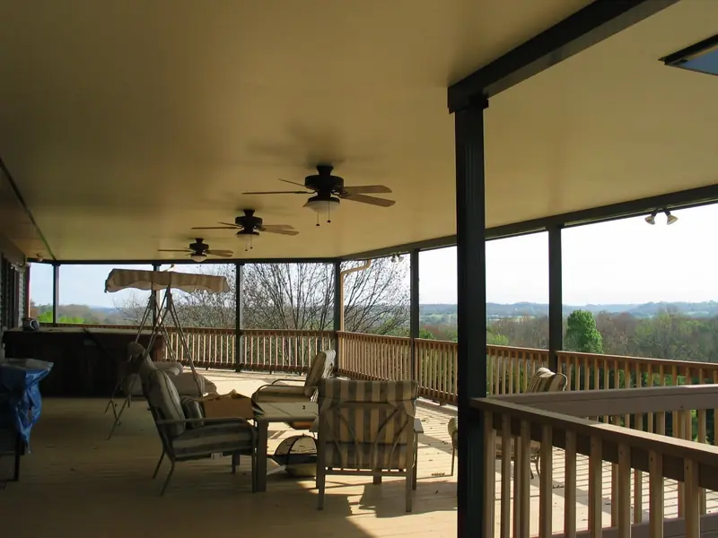 Covered deck with ceiling fans, outdoor furniture and a view across rolling hills