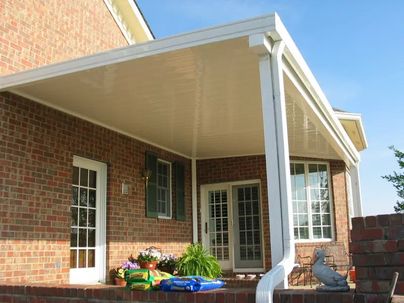 Patio cover with a ceiling fan over French doors on a brick home