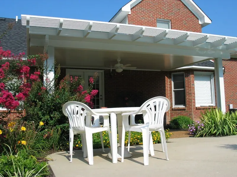 Patio cover with a lattice edge over a patio table, framed by crape myrtles