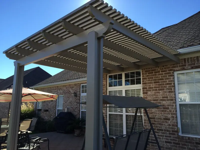 Bronze aluminum pergola over a patio swing on a brick home