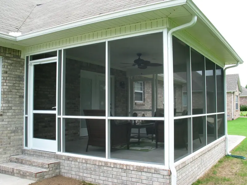 White aluminum screen room with a screen door, built on a brick knee wall