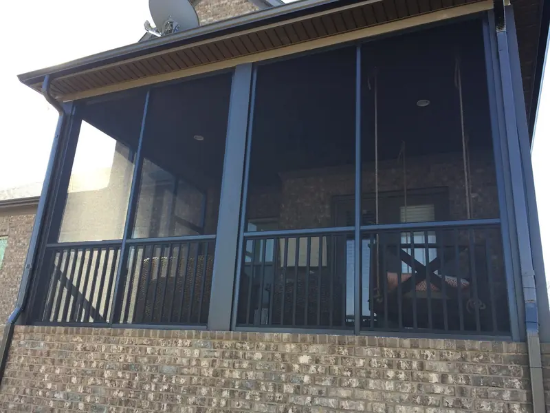 Bronze-framed screen porch with railing on a brick home
