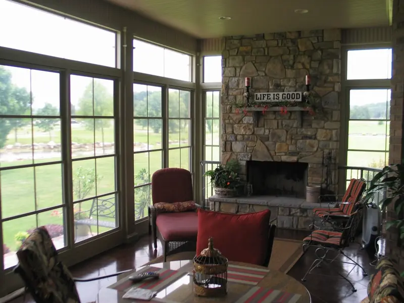 Sunroom interior with a stone fireplace and windows on three sides