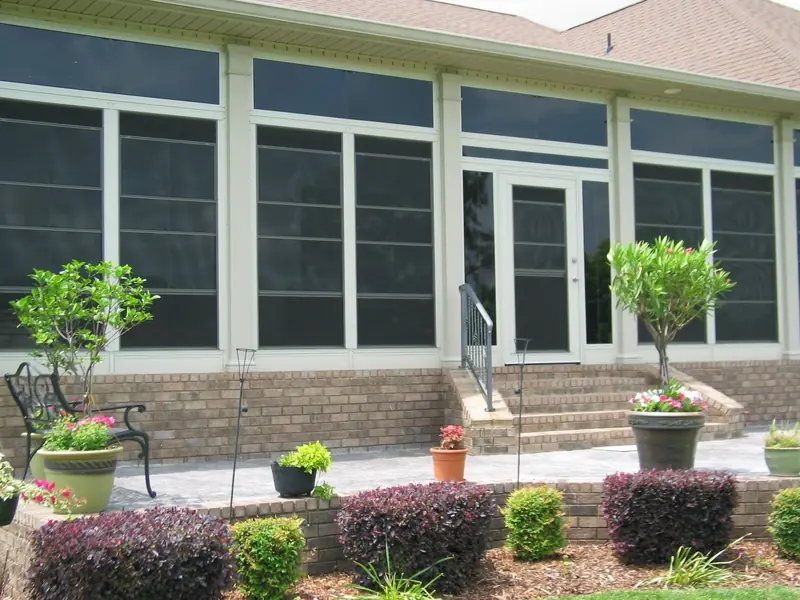 Sunroom with tall windows above a brick knee wall, with potted plants out front