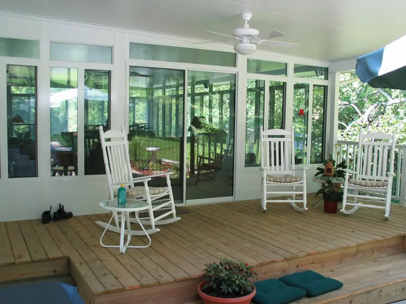 Rocking chairs on a wood floor inside a sunroom with a ceiling fan