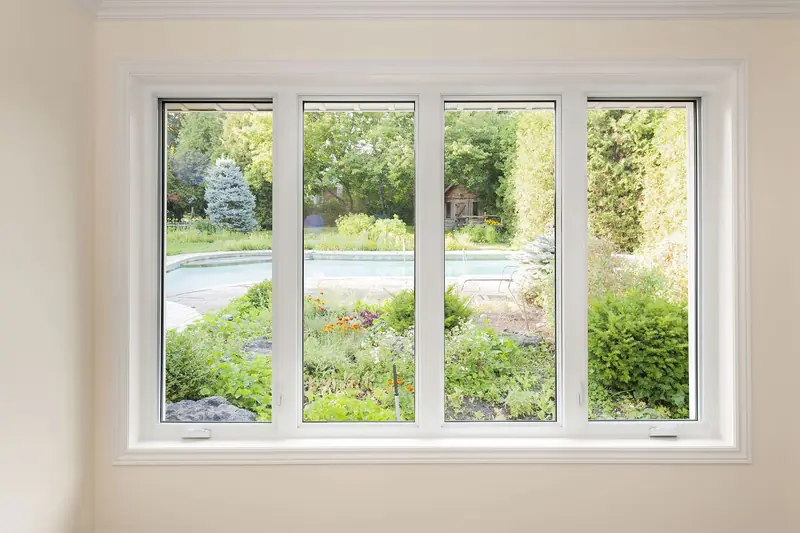 Interior view through a four-panel window onto a garden and pool